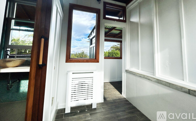 A white interior with a window showing a blue sky and trees outside.