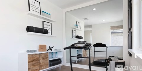 A gym room with a treadmill, weights, and a mirror.