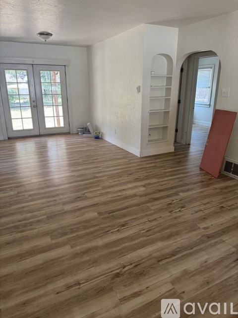 A room with wooden flooring and a red object on the floor.