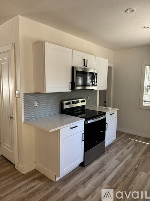 A kitchen with white cabinets and a black stove top oven.