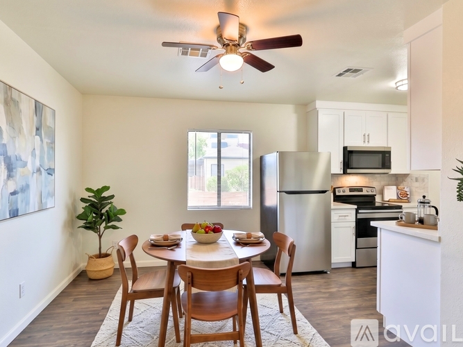 A kitchen with a table and chairs in the foreground and a refrigerator, microwave, and oven in the background.