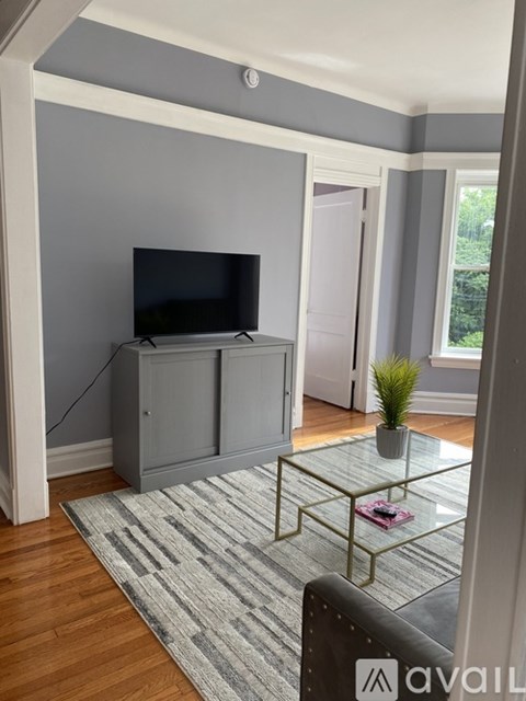 A living room with a television and a glass coffee table.