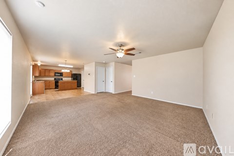A spacious room with a carpeted floor and a ceiling fan.