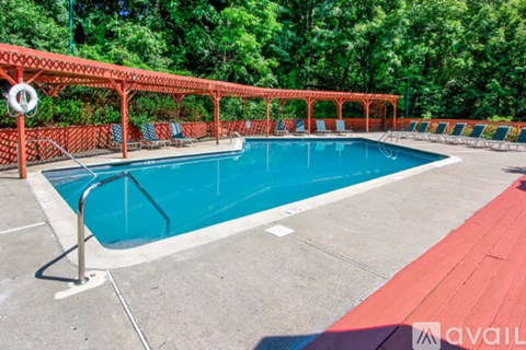 A pool surrounded by a red fence and trees.