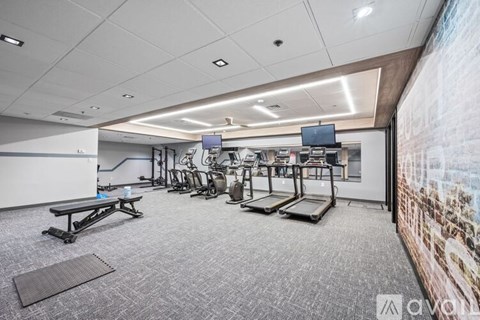 A gym room with treadmills, elliptical machines, and a bench.