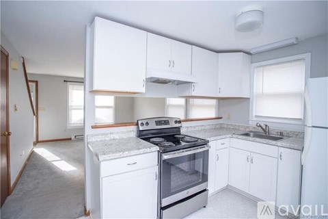 A kitchen with white cabinets and appliances.