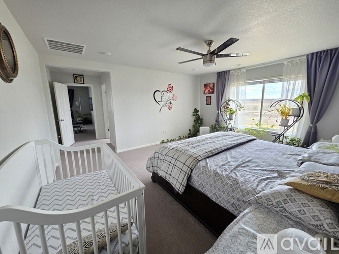 A bedroom with a white crib and a bed with grey bedding.