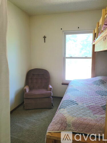 A bedroom with a bed, chair, and window.