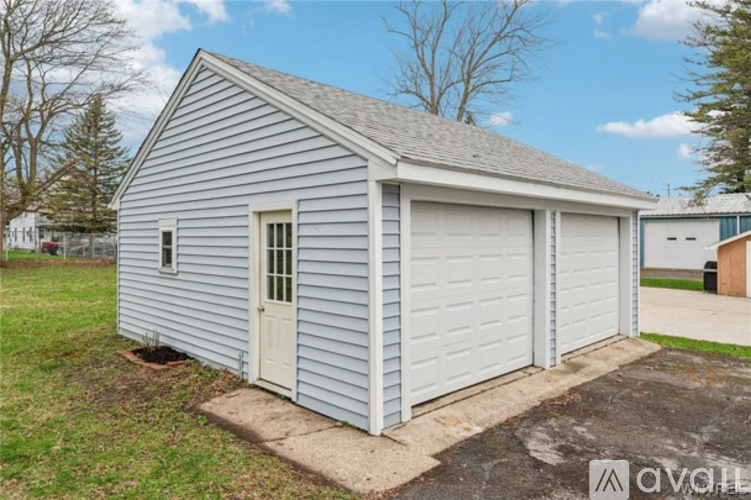 A two-car garage with a white door and windows is situated in a grassy area.