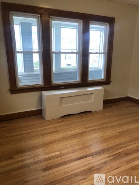 A room with wooden floors and a window with a white frame.