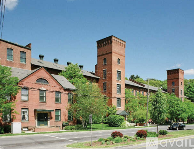A large red brick building with a tower in the middle of a green lawn.