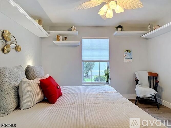 A kitchen with white cabinets and appliances, a ceiling fan, and a dining table with chairs.