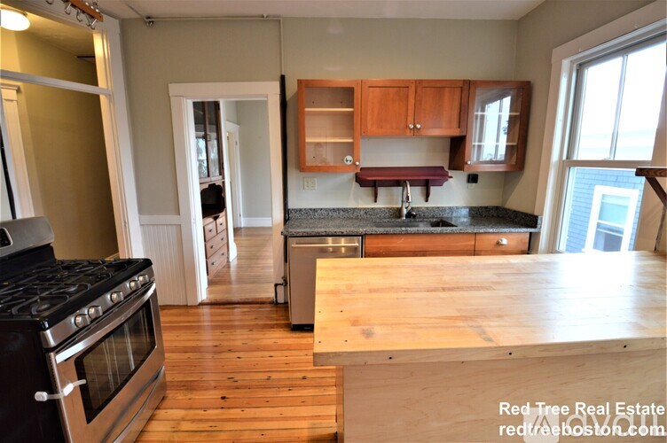 A kitchen with a stove top oven and wooden floors.