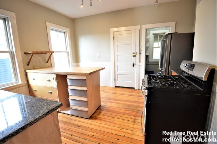 A kitchen with a black stove top oven and wooden floors.