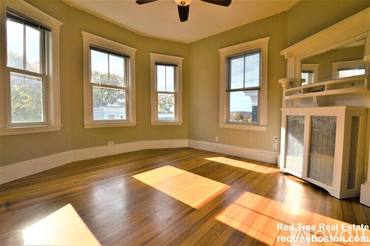 A room with a ceiling fan and a wood floor.