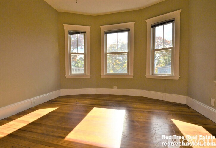 A room with wooden floors and two windows.