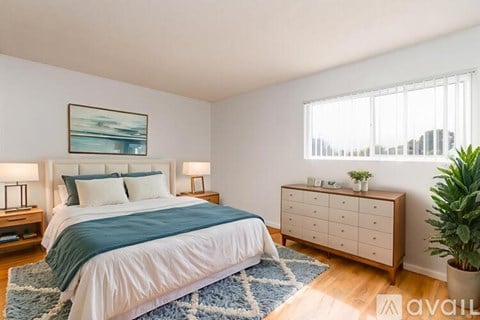 A bedroom with a bed, nightstands, and a plant.