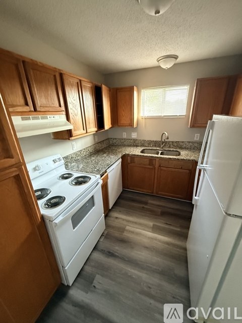A kitchen with wooden cabinets and a white stove top oven.