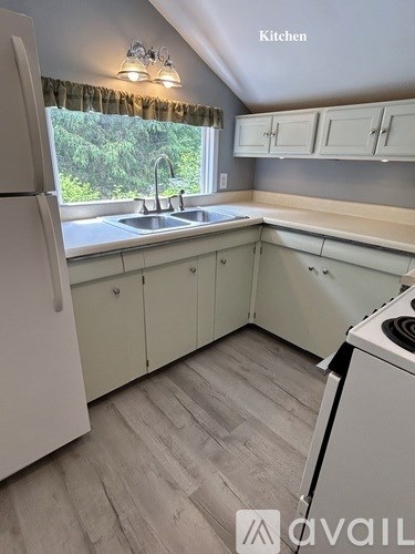A kitchen with a white refrigerator and cabinets.