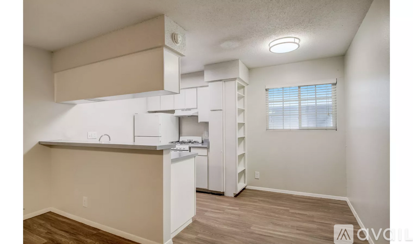 A kitchen with white cabinets and a window with blinds.