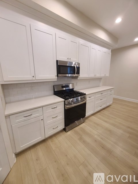 A kitchen with white cabinets and a black stove top oven.