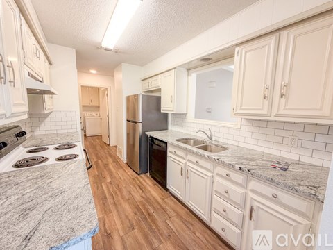 A kitchen with a granite counter top and wooden floors.