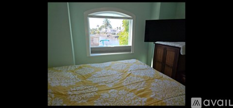 A bedroom with a bed and a window overlooking a pool.