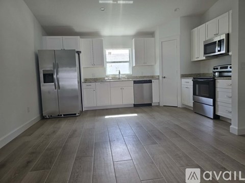 A kitchen with white cabinets and a wooden floor.