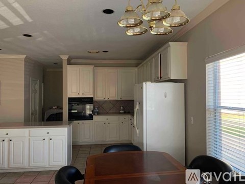 A kitchen with white cabinets and a white refrigerator.