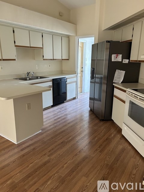 A kitchen with a black fridge and white cabinets.