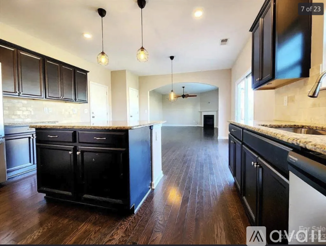 A kitchen with black cabinets and a wooden floor.
