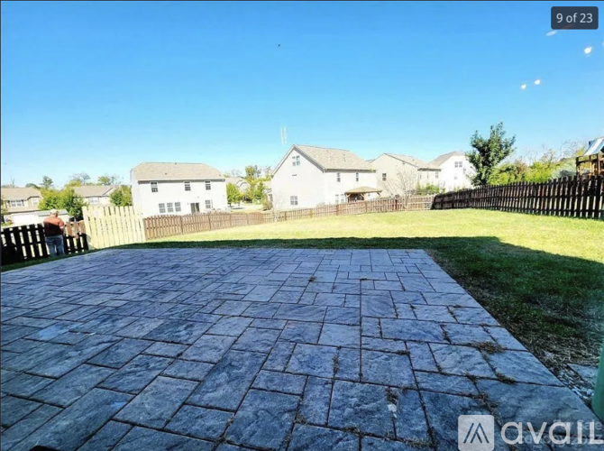 A paved walkway leads to a white house with a black fence.