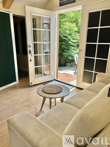 A living room with a couch, a coffee table, and a glass door leading outside.