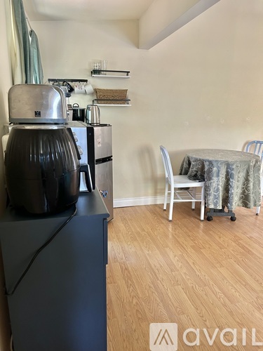 A kitchen with a black fridge, a silver toaster, and a table with a striped tablecloth.