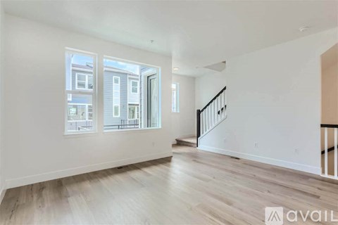 A spacious room with wooden floors and a staircase leading to another floor.