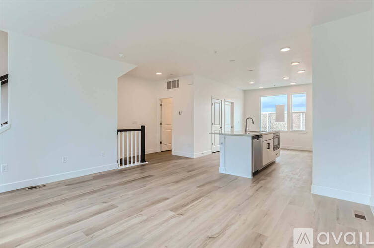 A spacious living room with wooden flooring and white walls.