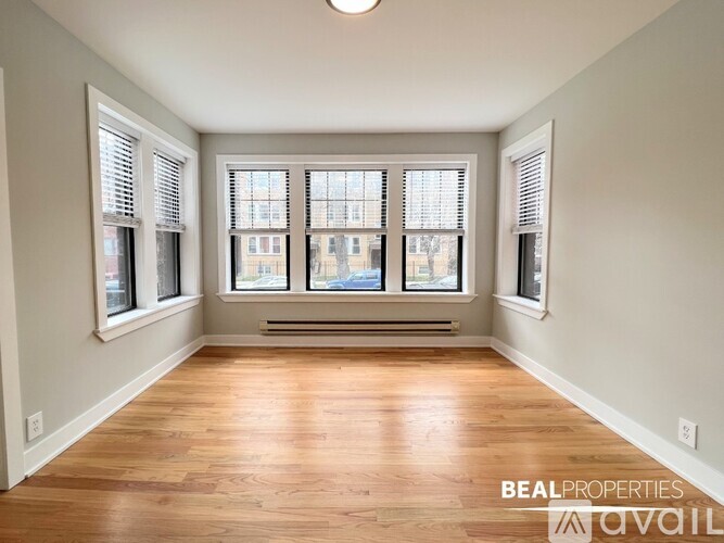 A spacious room with wooden floors and large windows.