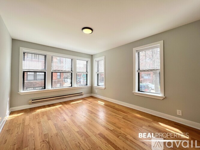 A room with wooden floors and two windows.
