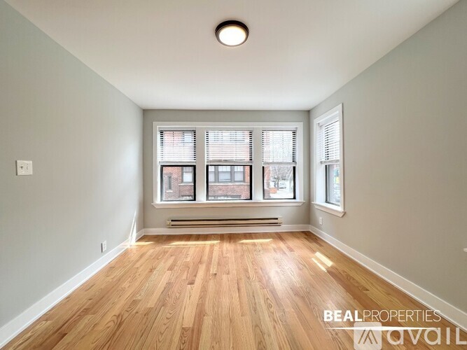 A room with wooden floors and a window with blinds.
