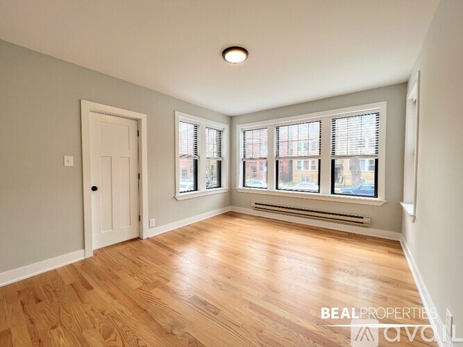 A room with wooden flooring and a window with blinds.