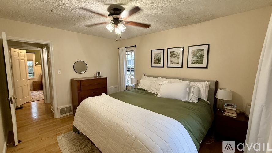 A bedroom with a bed, a ceiling fan, and pictures on the wall.