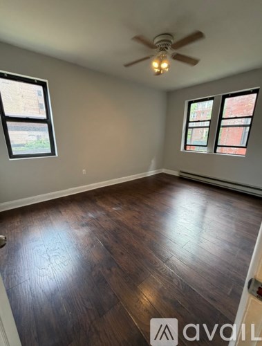 A room with a ceiling fan and wood flooring.