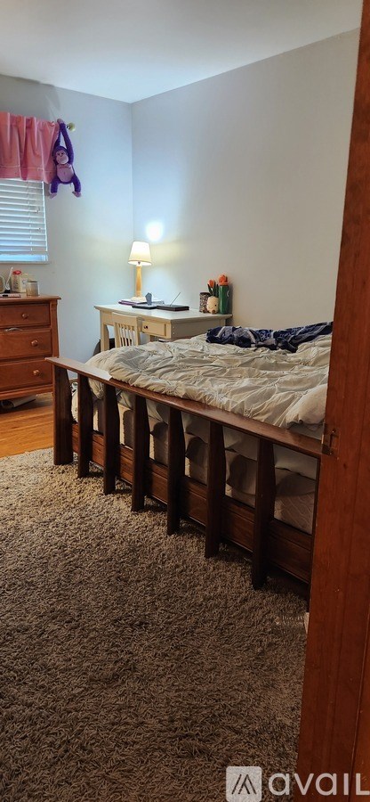 A bedroom with a bed, dresser, and window with curtains.