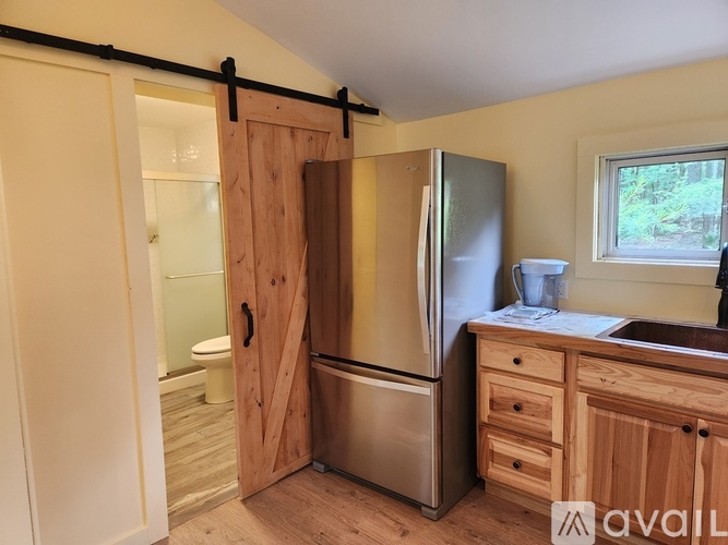 A kitchen with a wooden door and a stainless steel refrigerator.