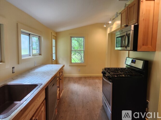 A kitchen with wooden cabinets and a black dishwasher.