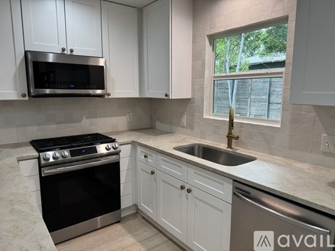 A kitchen with a black stove top oven and a stainless steel sink.