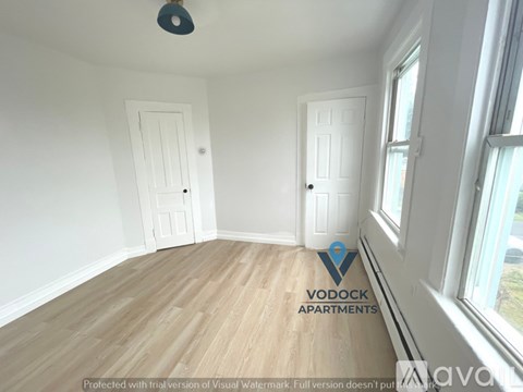 A room with wooden flooring and two doors, one of which is open.