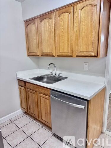 A kitchen with wooden cabinets and a stainless steel dishwasher.