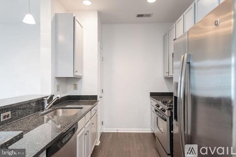 A kitchen with a stainless steel refrigerator and a black countertop.