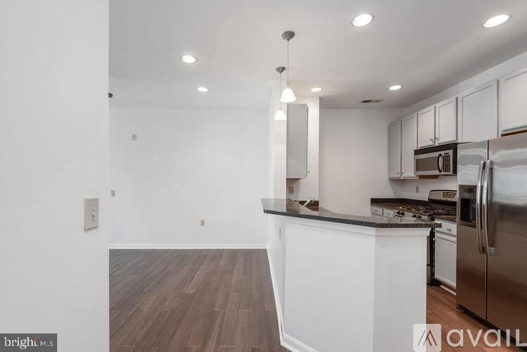 A kitchen with white cabinets and a wooden floor.